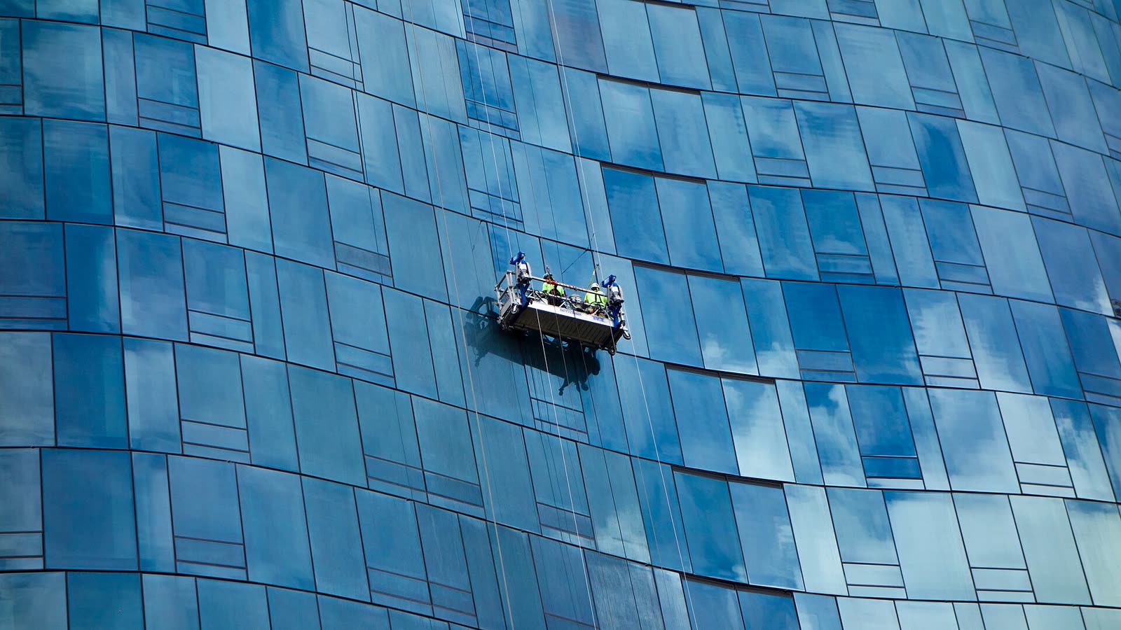 Arbeitskorb an einer blauen Glasfassade während der Fensterreinigung
